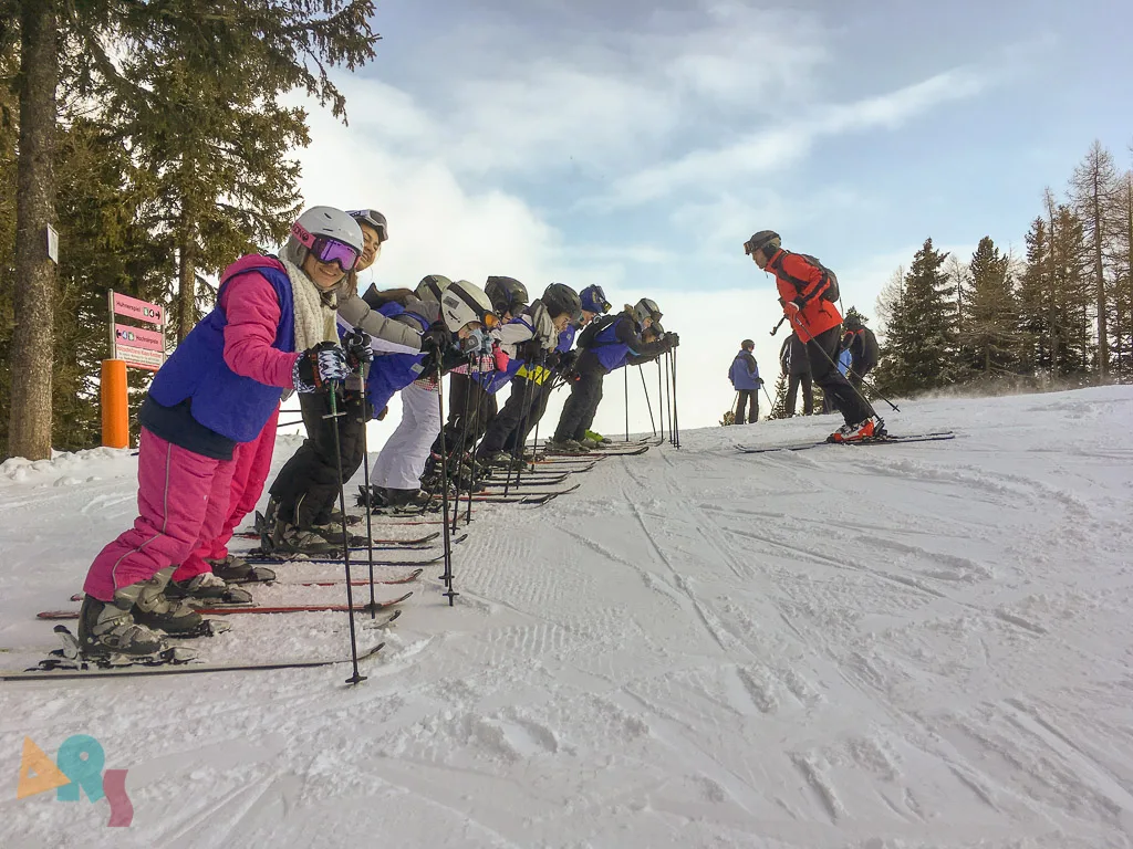 Skigruppe wartet nebeneinander auf der Piste.